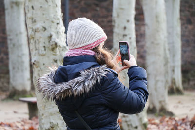 Rear view of woman photographing with smart phone