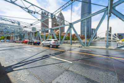 Cars on bridge against sky in city