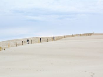 Low angle view of people walking on sand dune at desert