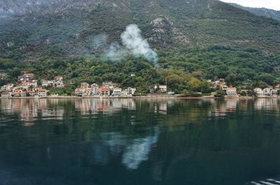 Scenic view of lake by buildings against mountain