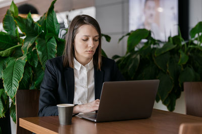 Businesswoman using laptop while sitting at table