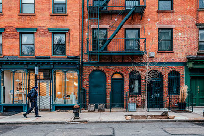 Man walking on footpath by building