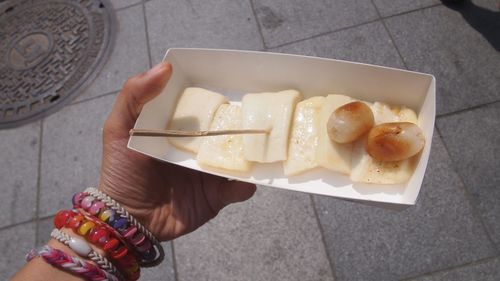 Cropped hand holding dessert in container on walkway