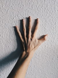 Cropped hand touching white wall