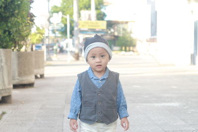 Portrait of toddler  standing on street in city