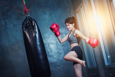 Young woman punching boxing bag at gym