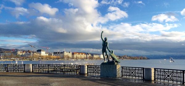 Statue in city against cloudy sky