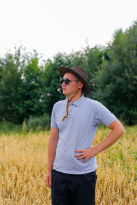 Crop and harvest. portrait of farmer standing in gold wheat field with blue sky in background. young