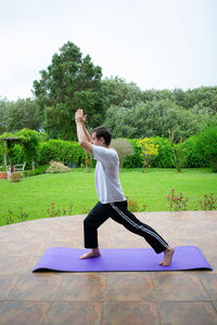 Full length of man with arms raised on grass against sky