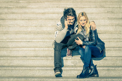 Full length of young woman using mobile phone in city