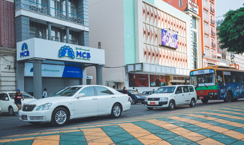 Vehicles on road by buildings in city