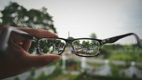 Close-up of hand on sunglasses against clear sky