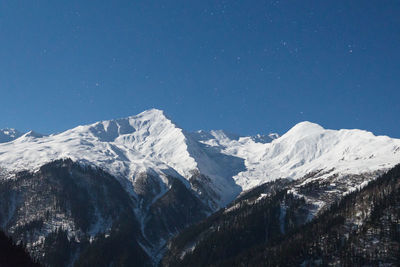 Scenic view of snowcapped mountains against clear blue sky