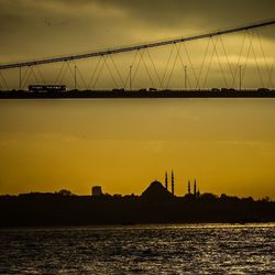 Suspension bridge over river at sunset