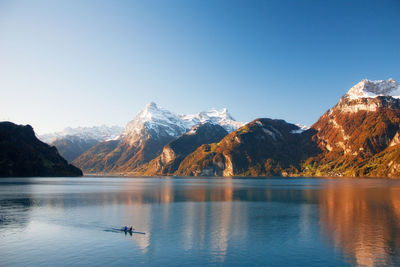 Scenic view of lake and mountains against clear blue sky