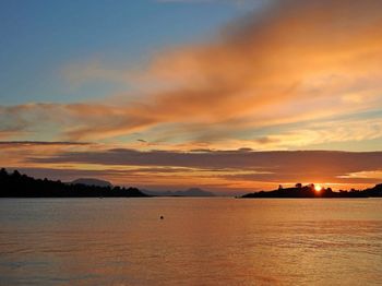 Scenic view of sea against dramatic sky during sunset