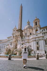 Rear view of woman walking against historical building