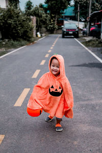 Portrait of happy girl with umbrella on road in city