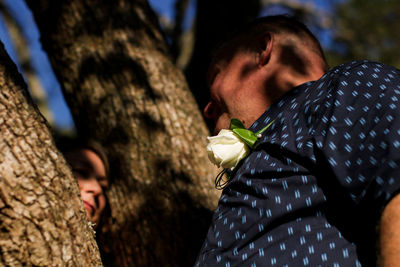 Midsection of man standing by tree trunk