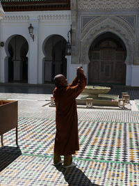 Rear view of man standing at temple against building