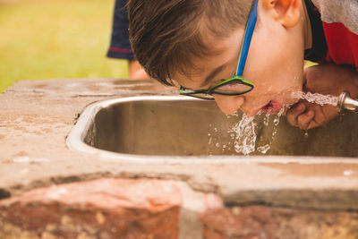 Close-up of boy drinking water from faucet
