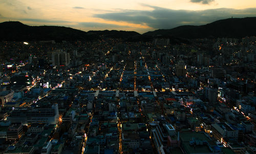 Aerial view of illuminated city against sky at sunset