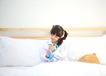 Young woman sitting on bed at home