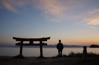 Silhouette man standing at seaside during sunset