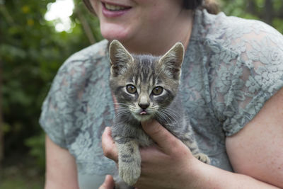 Midsection of woman holding cat outdoors