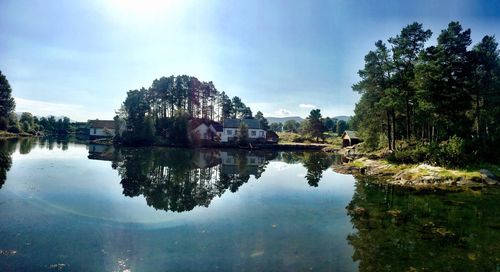 Reflection of trees and buildings in lake against sky