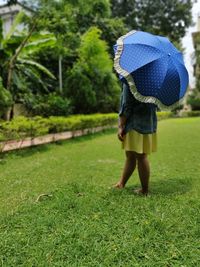 Rear view of woman with umbrella on field