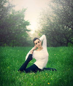 Portrait of woman sitting on grass in field