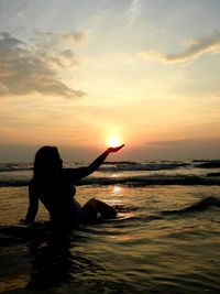 Silhouette woman on beach against sky during sunset