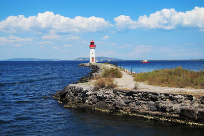 Lighthouse by sea against sky