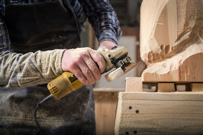 Close up experienced carpenter in work clothes and small buiness owner processes the board 