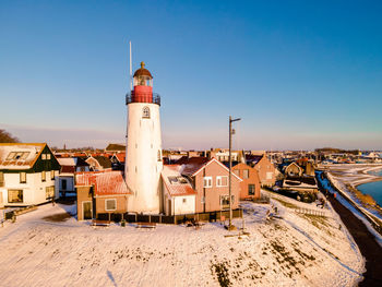 Lighthouse on beach against buildings in city