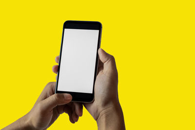 Low section of person using smart phone against yellow background