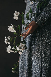 Midsection of woman holding white flowering plant