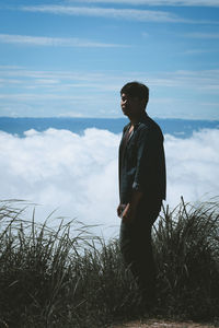 Young man standing against cloudscape on mountain
