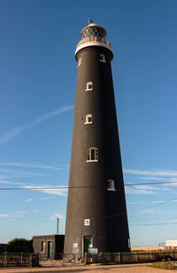 Low angle view of lighthouse by building against sky