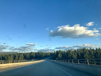 Road by trees against sky