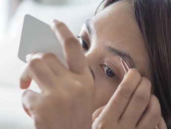 Close-up of woman removing eyebrows