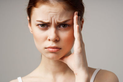 Close-up portrait of serious young woman against gray background