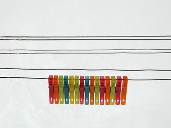 Close-up of multi colored clothespins hanging on wire against clear sky