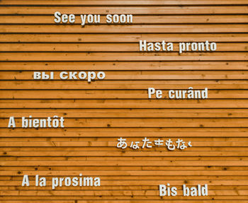 Close-up of information sign on wooden wall