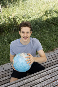 Portrait of young woman holding globe on field