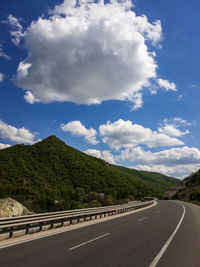 Empty road by mountains against sky