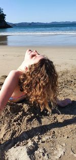 Midsection of young woman at beach against sky