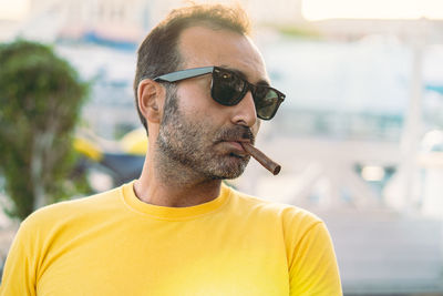 Man wearing sunglasses while smoking cigar outdoors
