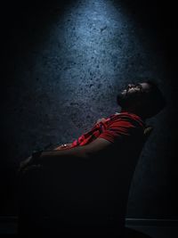 Side view of young man lying on wall